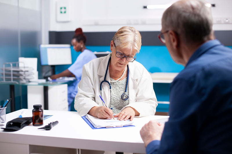 Dr sat across patient signing a form on a clipboard