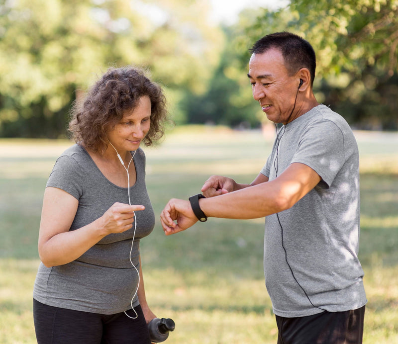 Two people outside exercising with one showing the other their fitness watch